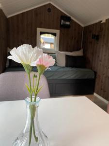 a vase with flowers on a table in a room at Gresslifoss Camping in Gressli