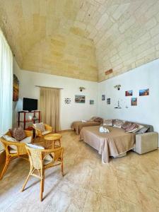 1 dormitorio con 2 camas, sofá y sillas en L'ANTICA PIETRA Casa Vacanza Salento, en Poggiardo