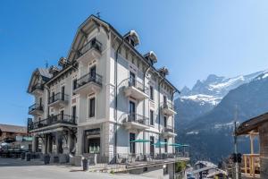a large white building in front of a mountain at Hôtel National Resort & Spa in Champéry