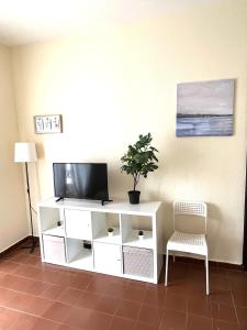 un centro de entretenimiento blanco con TV y silla en Camp Nou Apartment WiFi, en Barcelona