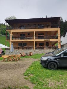 a building with a car parked in front of it at Vila Bianca Dragusin in Moieciu de Sus