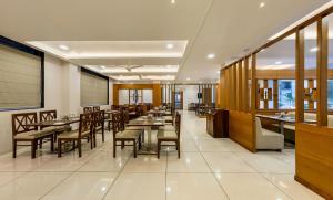戈尔哈布尔Hotel Grand Indu, 3 Star Kolhapur的餐厅里有桌椅的餐厅
