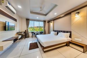 ein Hotelzimmer mit einem Bett, einem Schreibtisch und einem Tisch in der Unterkunft Hotel Grand Indu, 3 Star Kolhapur in Kolhapur