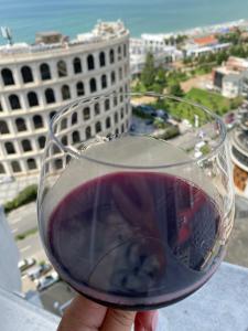 a person holding a glass of red wine at Batumi - Orbi Sea Tower & Residence in Batumi