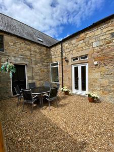 a patio with a table and chairs in front of a stone building at The Old Vicarage in Berwick-Upon-Tweed