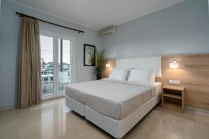 a bedroom with a large bed and a balcony at GrecoInn Grekas Classic Hotel in Nei Poroi