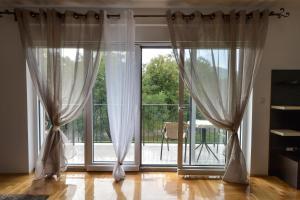 Habitación con ventana grande con cortinas blancas. en Park Srce Apartments, en Arandjelovac