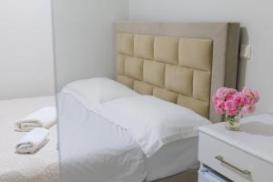 a white bedroom with a bed and flowers in a mirror at Saranda Landscape in Sarandë