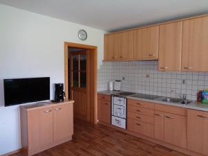 a kitchen with wooden cabinets and a flat screen tv at Althuberhof in Planca di Sopra