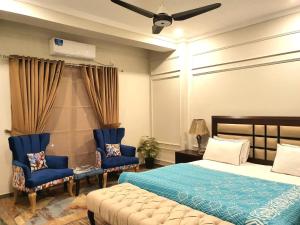 a bedroom with a bed and two blue chairs at The Millenial Apartments & Suites Bahria Town in Rawalpindi