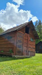 a wooden cabin with a door in the grass at Chatka Gargamela in Mikołajki