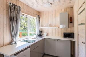 una pequeña cocina con fregadero y ventana en Domki Aqua Holiday, en Pobierowo