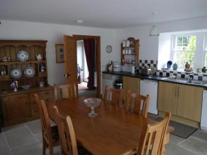 cocina y comedor con mesa de madera y sillas en Old Coach House en Moniaive