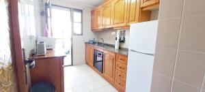a kitchen with wooden cabinets and a white refrigerator at Apartament Playa Arenales in Arenales del Sol