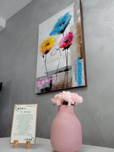 GRETA'S HOUSE في Comitini: مزهرية وردية مع الزهور على طاولة مع لوحة
