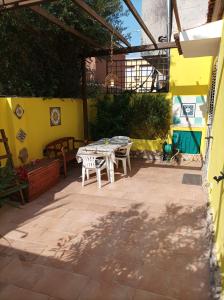 un patio con una mesa y una pared amarilla en Casa La Fornace, en La Maddalena