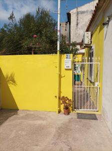una cerca amarilla junto a una casa amarilla con una puerta en Casa La Fornace, en La Maddalena