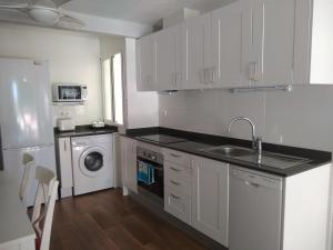 uma cozinha branca com um lavatório e uma máquina de lavar louça em Apartamento Vivemar em El Campello