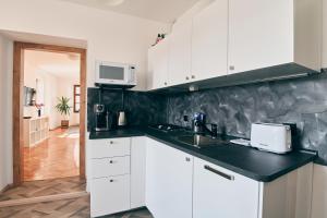 una cucina con armadi bianchi e piano di lavoro nero di Kutna Hora new apartment a Kutná Hora