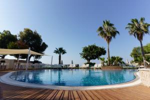 a swimming pool with palm trees in the background at Costa Luvi Hotel Bodrum - All Inclusive in Gümbet