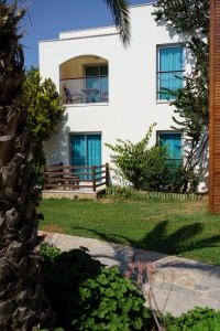a white house with blue windows and a porch at Costa Luvi Hotel Bodrum - All Inclusive in Gümbet