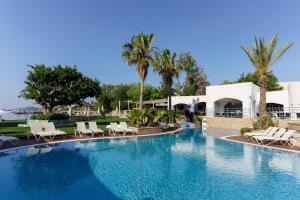 a large swimming pool with chairs and palm trees at Costa Luvi Hotel Bodrum - All Inclusive in Gümbet
