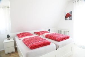 zwei rote Kissen auf einem weißen Bett in einem Zimmer in der Unterkunft Ferienwohnung 3land Reisen in Neuenburg am Rhein