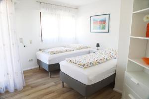 2 Betten in einem Zimmer mit weißen Wänden und Holzböden in der Unterkunft Ferienwohnung 3land Reisen in Neuenburg am Rhein