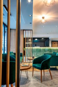 a lobby with green chairs and a table at Ador Hotel in Pristina