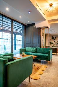 a living room with green couches and a table at Ador Hotel in Prishtinë +44 photos