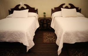 La Casa del General Hotel Boutique في هيدالجو ديل بارال: سريرين بملاءات بيضاء في غرفة النوم