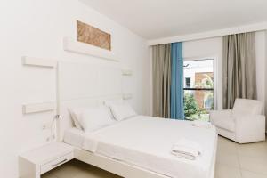 a white bedroom with a bed and a chair at Costa Luvi Hotel Bodrum - All Inclusive in Gümbet