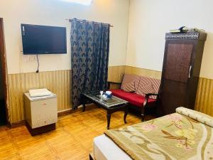Habitación con cama, sofá y TV. en Hotel Mehran Multan en Multán