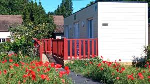 una casa con una valla roja junto a un campo de flores en B&B du Cerisier, diner sur demande, en Noyers