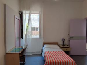 1 dormitorio con cama, escritorio y ventana en Hotel Villa Cecilia en Isquia