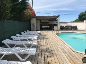 a row of white lounge chairs next to a swimming pool at La Bonne Mine in Le Fraysse