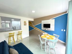 a living room with a blue accent wall and a table and chairs at Eu Amo Arraial Hospedagem - Luz do Sol Prainha in Arraial do Cabo