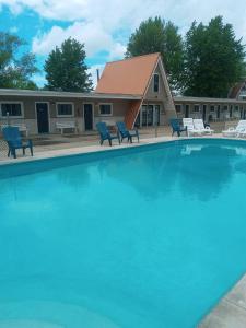 uma grande piscina com cadeiras e uma casa em The Palms Motel em Geneva-on-the-Lake