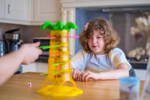 uma criança sentada à mesa a brincar com uma torre de brinquedos em Family Appartement 'MarieO' with Game Room and outdoor facilities em Gistel