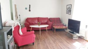 salon z czerwoną kanapą i stołem w obiekcie Cottage Halle-Hunneberg w mieście Vargön