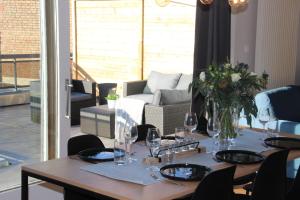 a dining room table with wine glasses and a couch at Family Appartement 'MarieO' with Game Room and outdoor facilities in Gistel
