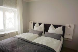 1 dormitorio con 1 cama con almohadas blancas y grises en Zauberhaftes Stadthaus, en Altötting