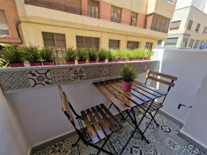 a balcony with two wooden benches and potted plants at Vive Valencia con playa y metro cerca in Valencia