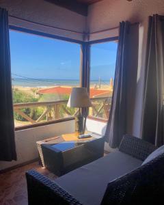 a living room with a table and chairs and a large window at El Mirador, Apartamento in Punta Del Diablo