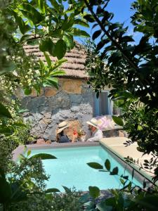 two people sitting on a bench next to a swimming pool at Is Cheas wine farm boutique hotel in San Vero Milis