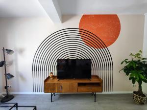 telewizor na komodzie w salonie z malowidłem ściennym w obiekcie Le Rainbow - Grand studio avec terrasse w mieście Dunkierka