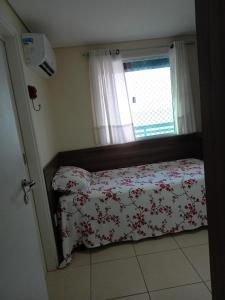 a bedroom with a bed with a floral bedspread and a window at Dunna Barcane in Natal