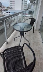a glass table and two chairs on a balcony at AQUAMARINA 4 in Puerto Madryn