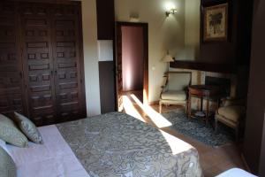 a bedroom with a bed and a door and a chair at Finca Rincón de la Vega in Los Cortos