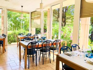 a dining room with tables and chairs and windows at Village vacances Le Hameau des Oliviers in Vaison-la-Romaine